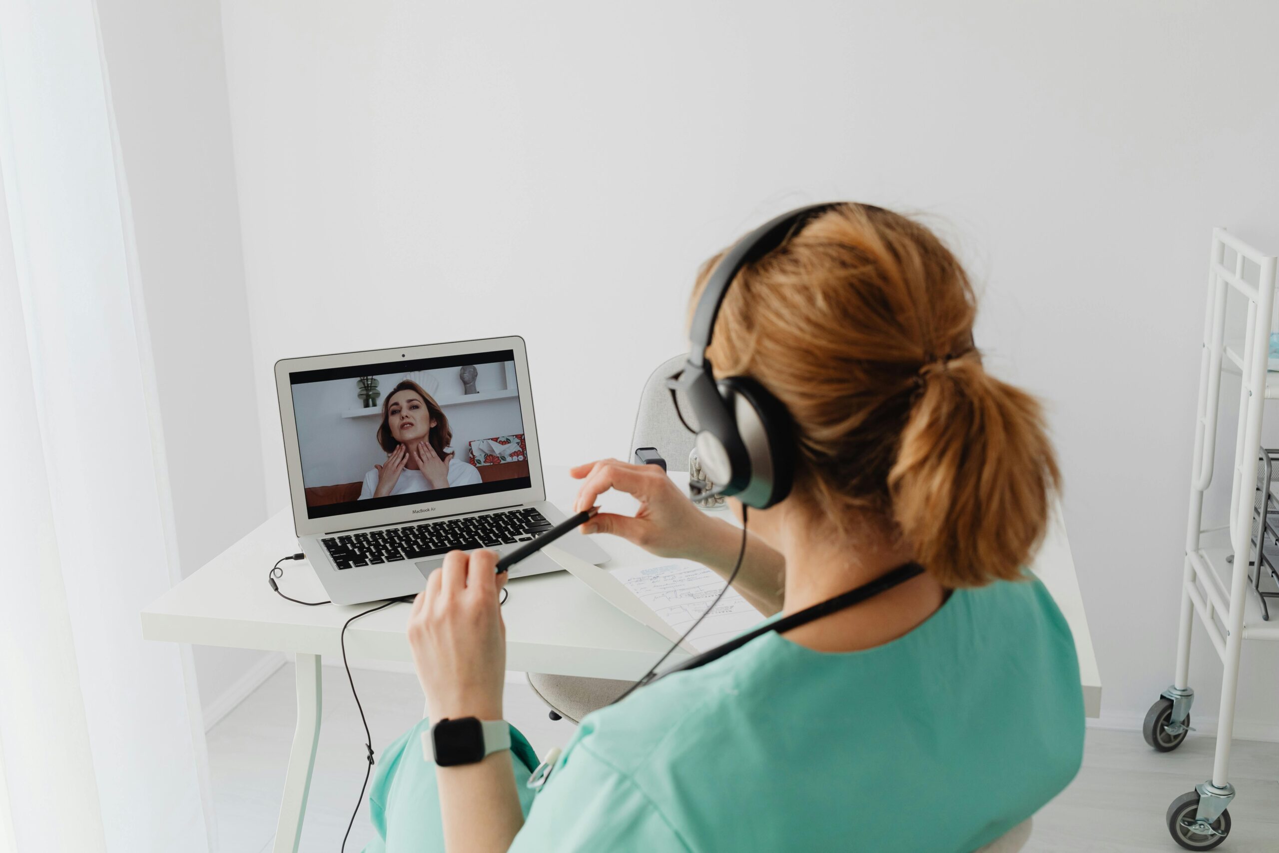 A doctor conducting an online consultation with a patient via laptop in a modern office setting.